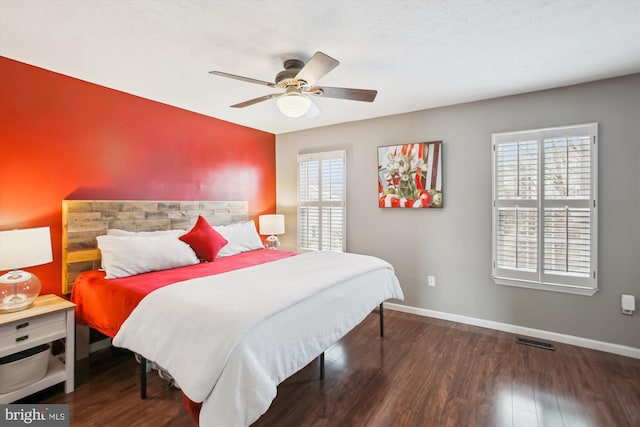 bedroom with multiple windows, dark hardwood / wood-style floors, and ceiling fan