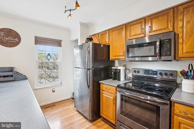 kitchen with stainless steel appliances, ornamental molding, and light wood-type flooring