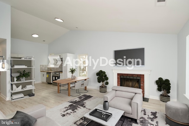 living room with vaulted ceiling, a brick fireplace, and light hardwood / wood-style flooring