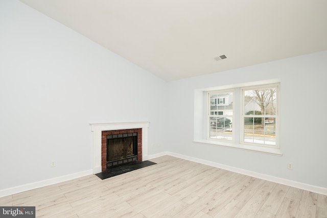 unfurnished living room with a brick fireplace and light hardwood / wood-style flooring