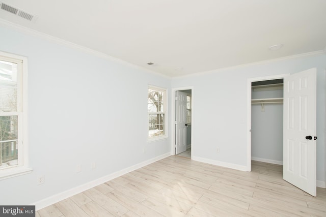 unfurnished bedroom featuring ornamental molding, a closet, and light wood-type flooring