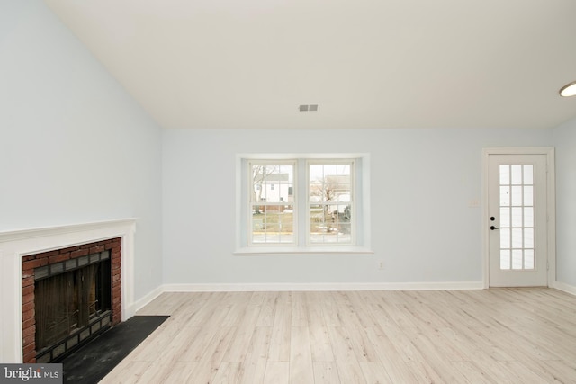 unfurnished living room featuring a wealth of natural light, a fireplace, and light hardwood / wood-style flooring