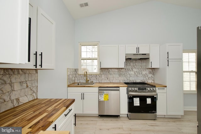 kitchen featuring stainless steel appliances, white cabinetry, and butcher block countertops