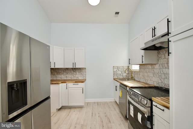 kitchen with butcher block counters, stainless steel appliances, and white cabinets