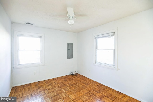 spare room featuring light parquet flooring, a textured ceiling, electric panel, and ceiling fan