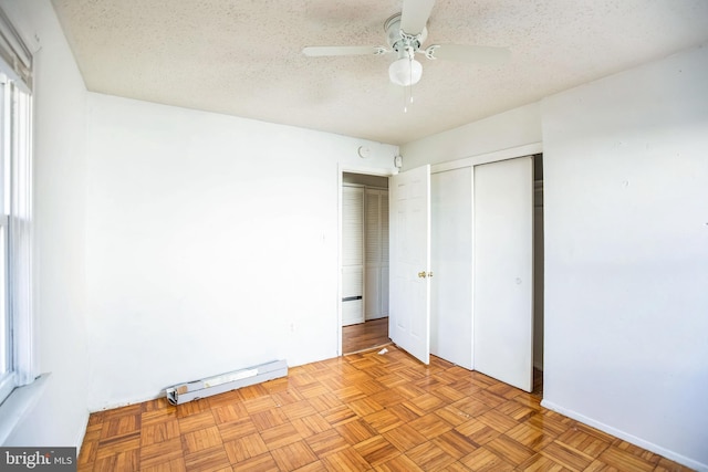 unfurnished bedroom with ceiling fan, a baseboard heating unit, light parquet flooring, and a textured ceiling