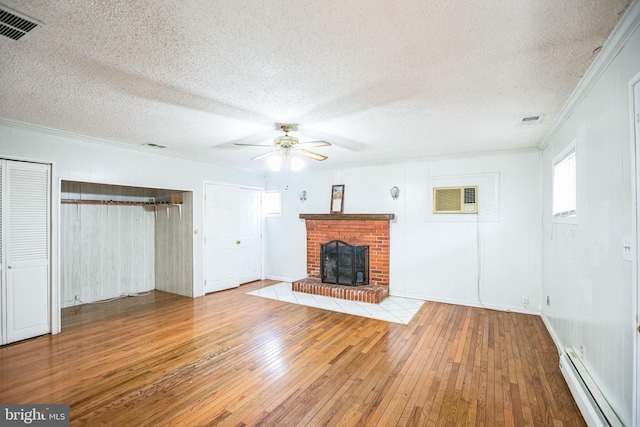 unfurnished living room with crown molding, wood-type flooring, a textured ceiling, a brick fireplace, and a baseboard radiator