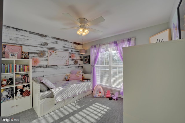 bedroom with wooden walls, ceiling fan, and carpet flooring