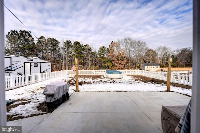 snow covered patio with grilling area and a shed