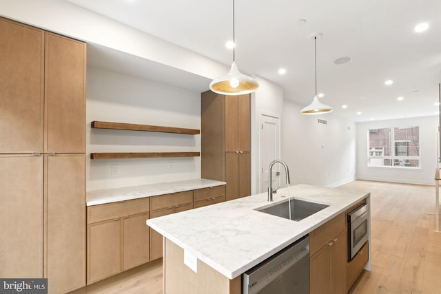 kitchen with sink, light wood-type flooring, stainless steel dishwasher, and a center island with sink