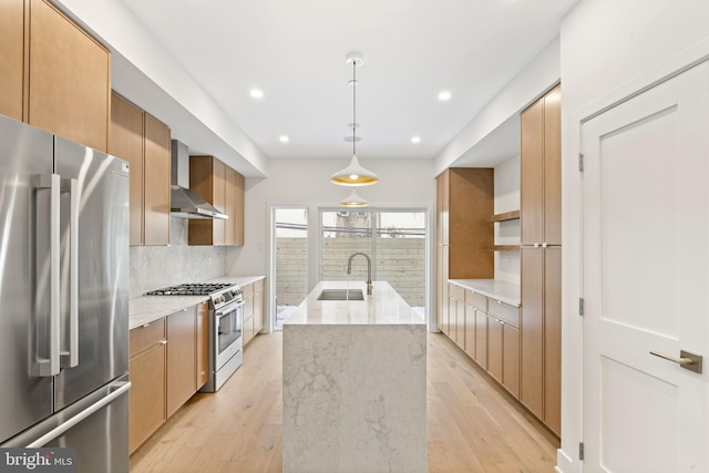 kitchen with appliances with stainless steel finishes, an island with sink, sink, backsplash, and wall chimney exhaust hood