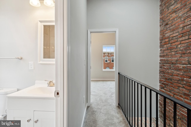 corridor featuring sink and light carpet