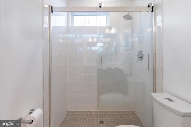 bathroom with a shower with shower door and toilet