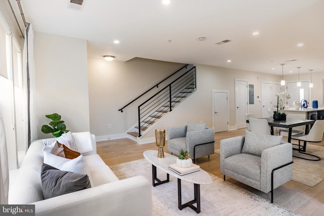 living room featuring electric panel and light hardwood / wood-style flooring