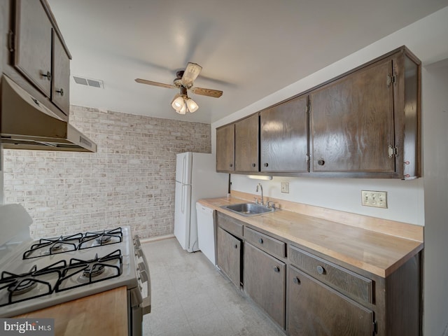 kitchen with ceiling fan, white appliances, brick wall, and sink