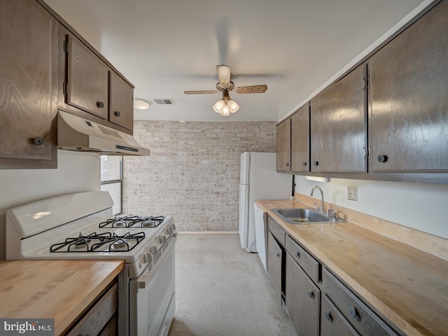 kitchen featuring sink, white appliances, wooden counters, ceiling fan, and brick wall