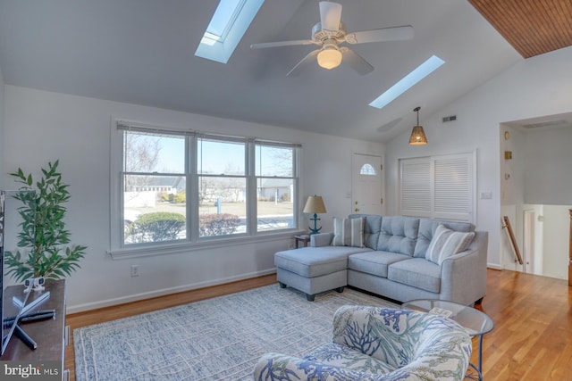 living room featuring ceiling fan, a skylight, high vaulted ceiling, and light wood-type flooring