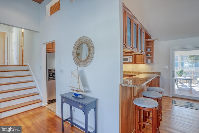 interior space featuring light stone counters, light hardwood / wood-style flooring, and stainless steel refrigerator with ice dispenser