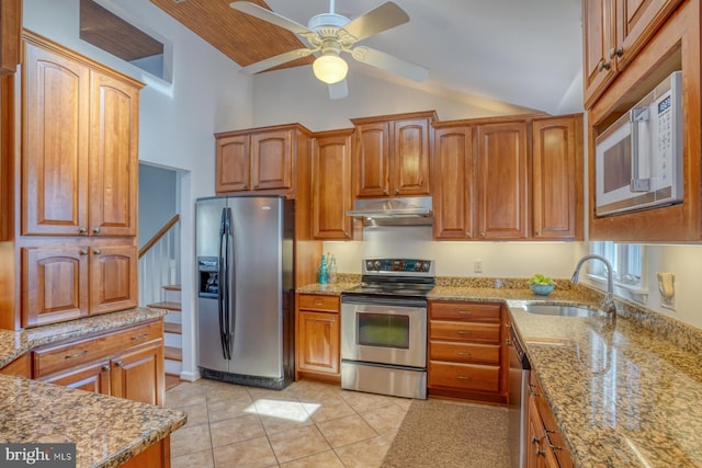 kitchen featuring light tile patterned flooring, lofted ceiling, sink, stainless steel appliances, and light stone countertops