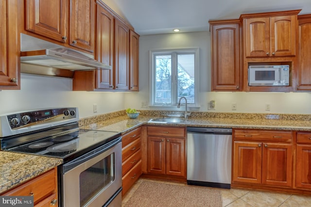 kitchen featuring light stone counters, stainless steel appliances, sink, and light tile patterned floors