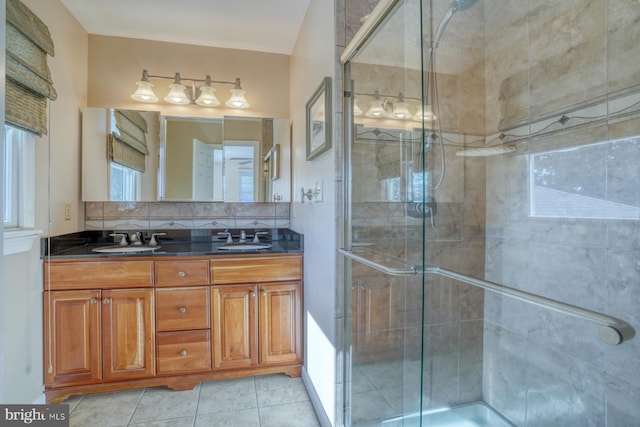 bathroom featuring vanity, decorative backsplash, a shower with door, and tile patterned floors