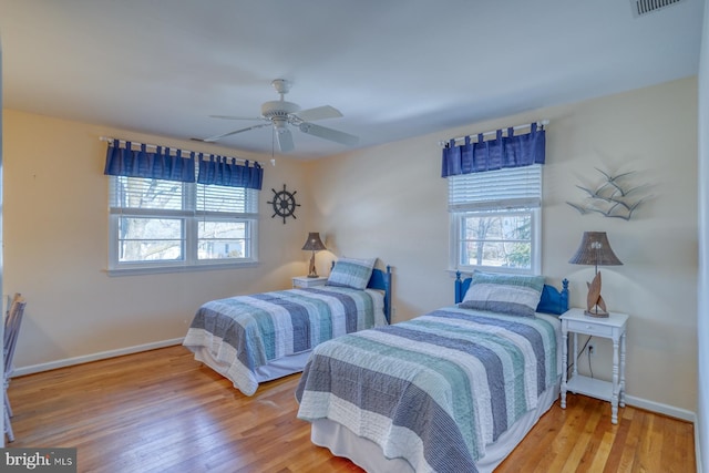 bedroom featuring hardwood / wood-style flooring, ceiling fan, and multiple windows