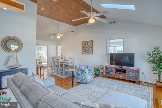 living room with ceiling fan, vaulted ceiling with skylight, and light hardwood / wood-style floors