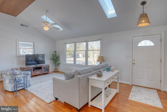 living room featuring wood-type flooring, a healthy amount of sunlight, and vaulted ceiling with skylight