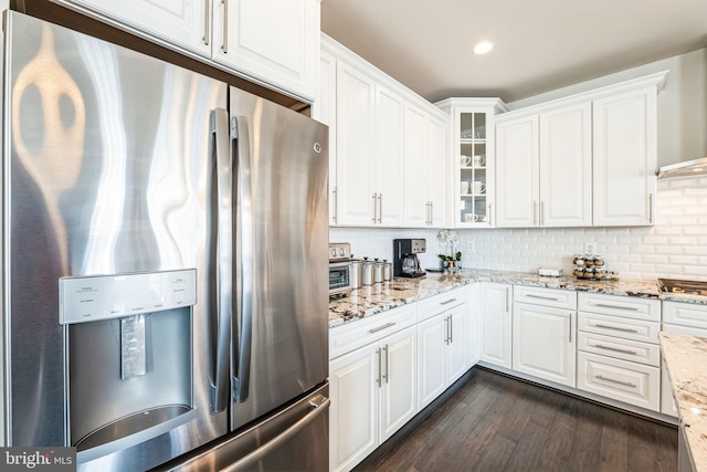 kitchen featuring stovetop, white cabinets, dark hardwood / wood-style flooring, stainless steel fridge, and light stone counters