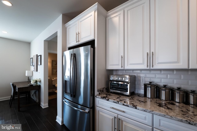 kitchen featuring stainless steel refrigerator with ice dispenser, dark hardwood / wood-style floors, light stone countertops, decorative backsplash, and white cabinets