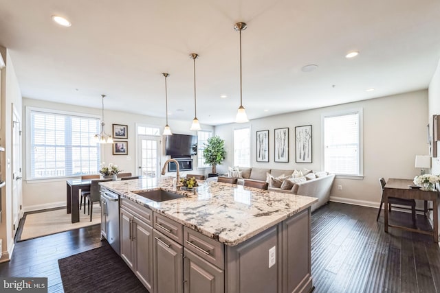 kitchen featuring sink, dishwasher, a kitchen island with sink, dark hardwood / wood-style floors, and light stone countertops