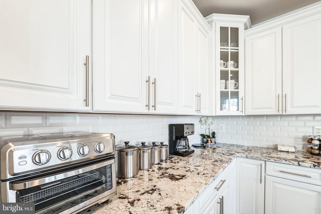 kitchen with light stone countertops, white cabinets, and decorative backsplash