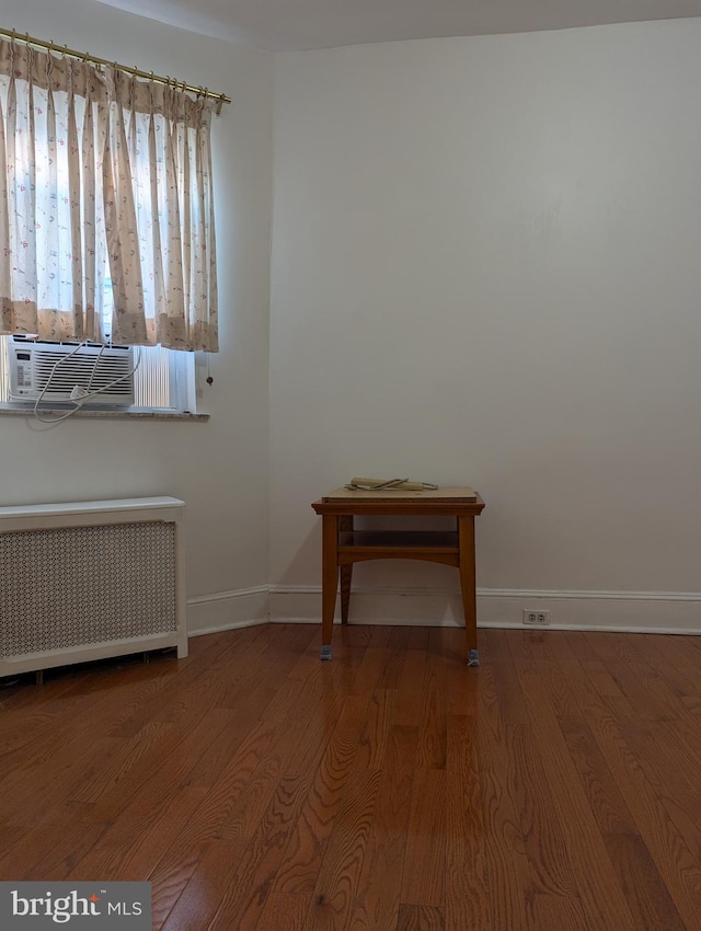 empty room with cooling unit, radiator, and hardwood / wood-style floors