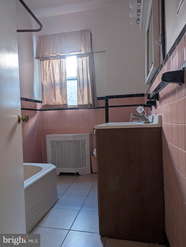 bathroom featuring tile walls, radiator, vanity, and tile patterned floors