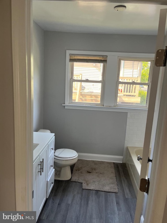 bathroom with vanity, hardwood / wood-style floors, a bathtub, and toilet