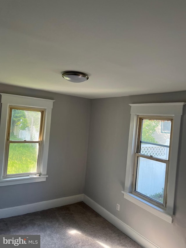 unfurnished room featuring plenty of natural light and carpet