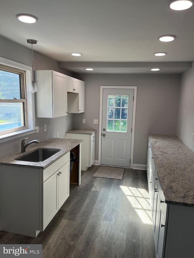 kitchen featuring stone countertops, pendant lighting, dark hardwood / wood-style floors, sink, and white cabinets