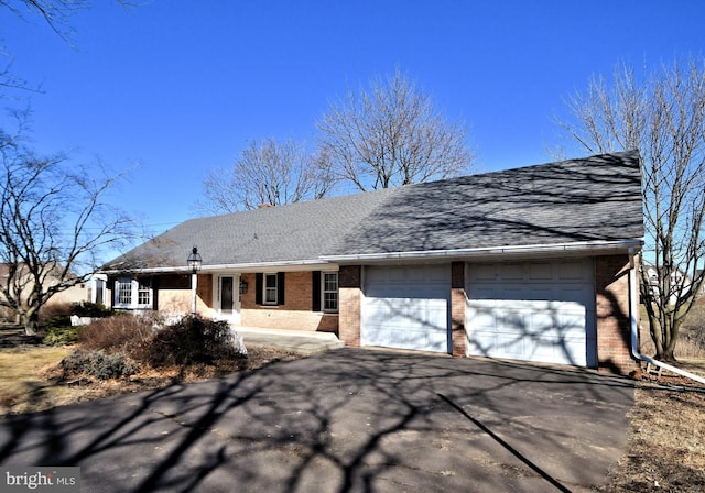 view of front facade with an attached garage, brick siding, driveway, and roof with shingles