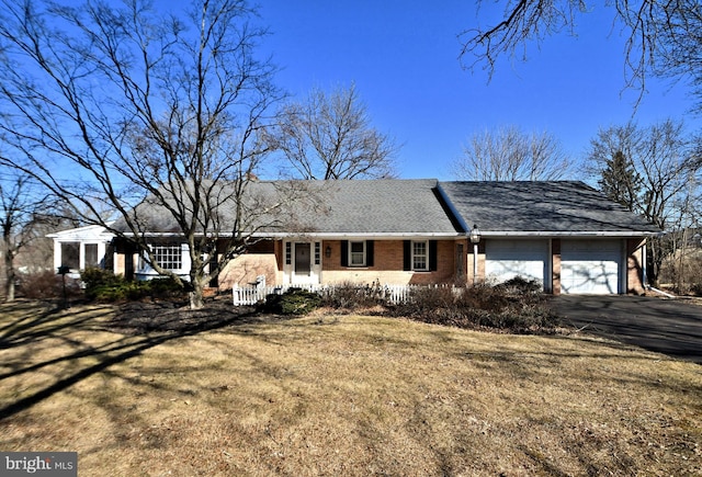 ranch-style house featuring aphalt driveway, brick siding, a garage, and a front yard