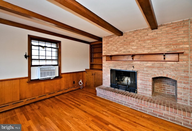 unfurnished living room featuring wainscoting, a brick fireplace, a baseboard heating unit, and wood finished floors