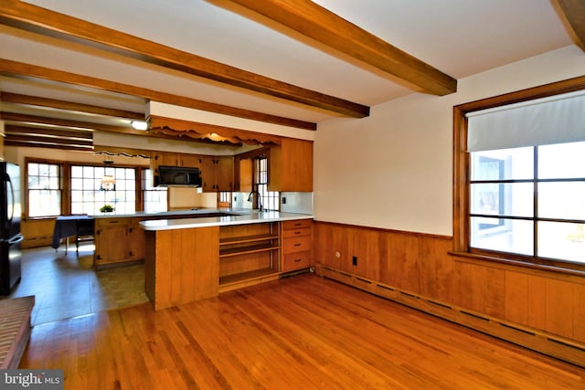 kitchen with brown cabinetry, baseboard heating, a peninsula, and black appliances