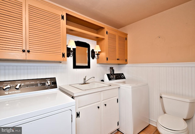 laundry area featuring washer and clothes dryer, a wainscoted wall, laundry area, light tile patterned flooring, and a sink