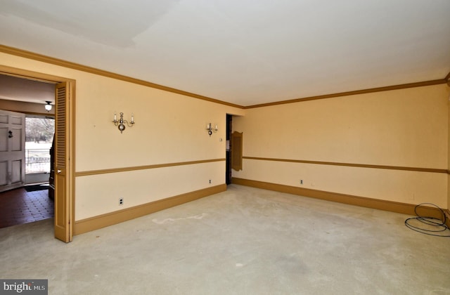 carpeted spare room featuring baseboards and ornamental molding