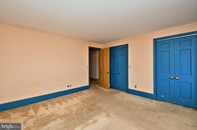 unfurnished bedroom featuring baseboards, carpet, and multiple closets