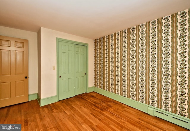 unfurnished bedroom featuring a closet, baseboards, and wood finished floors