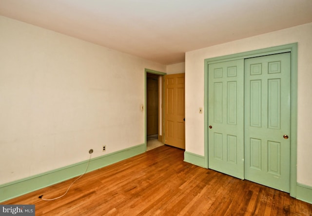 unfurnished bedroom featuring a closet, baseboards, and wood finished floors