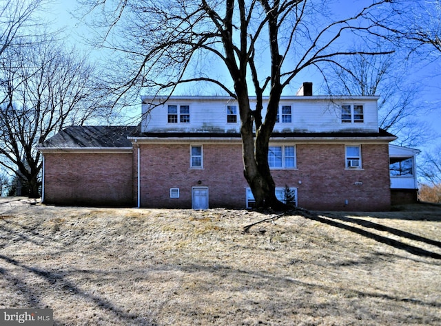 rear view of house with crawl space, brick siding, and a chimney