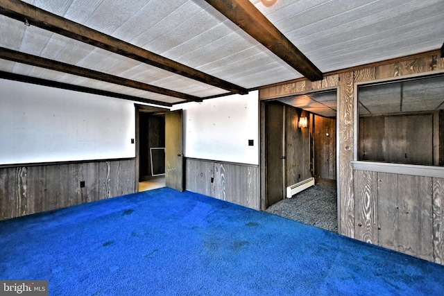 carpeted empty room featuring beamed ceiling, a wainscoted wall, a baseboard heating unit, and wood walls