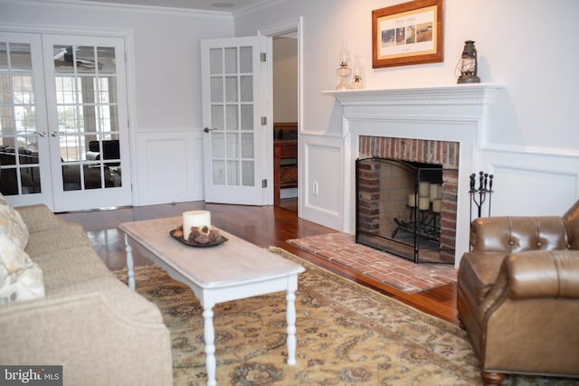 living room featuring ornamental molding, dark wood-type flooring, a fireplace, and french doors