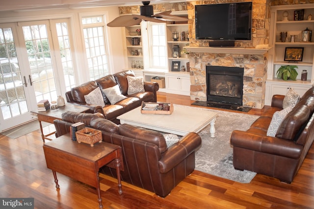 living room with hardwood / wood-style floors, built in shelves, and a fireplace